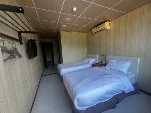 two twin beds in a room with a tv at 卡蹓英雄館 in Ma-tsu