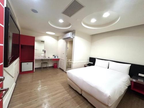 a bedroom with a large white bed and a kitchen at 柜富賓王旅店-台北館 Giant Rich King Plaza Hotel in Taipei