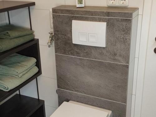 a bathroom with a toilet and a shelf with towels at Holiday home at the mill pond in Windeck