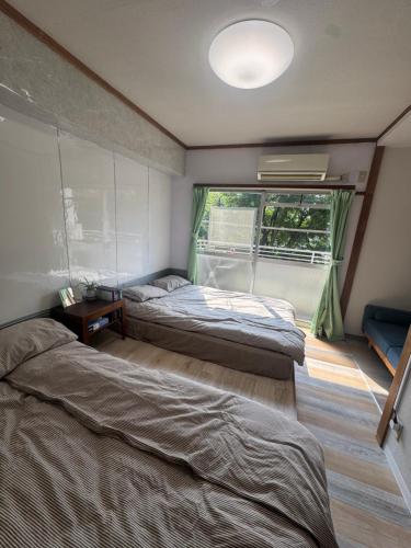 two beds in a room with a window at 和風2西北口 in Tokyo