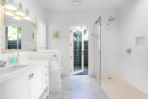 a white bathroom with a shower and a sink at Bahari House - Luxury Oceanfront Villa with Spectacular View, Pool, Spa and Dock in Hartswell