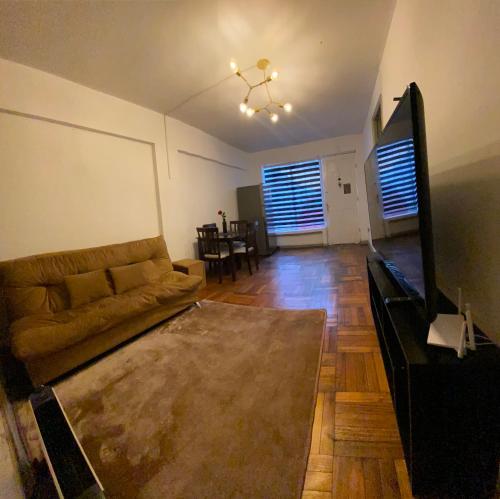 Una sala de estar con un sofá y un televisor de pantalla plana. en CASA ROMÁN Departamento en Providencia para 3 personas, en Santiago