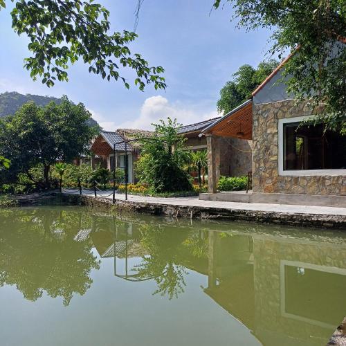a house with a pond in front of it at Hang Mua Luxury Homestay in Xuân Sơn