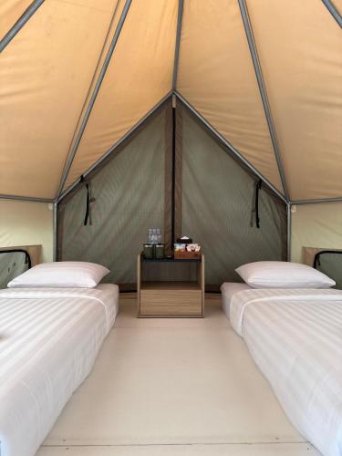 a tent with two beds and a table in it at JSI Resort Megamendung in Puncak