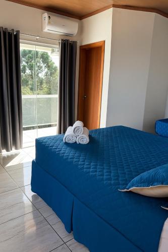 ein Schlafzimmer mit einem blauen Bett mit Handtüchern darauf in der Unterkunft Chácara Cidade da Divina Misericórdia in Araucária