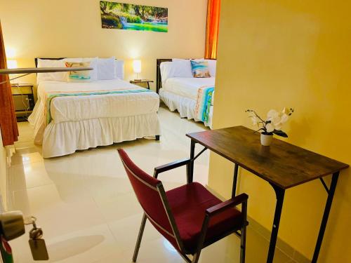 a room with two beds and a table and a chair at Clora Hotel 