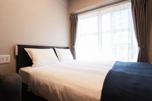 a bedroom with a large bed with a window at Advanced Stay Hakata in Fukuoka