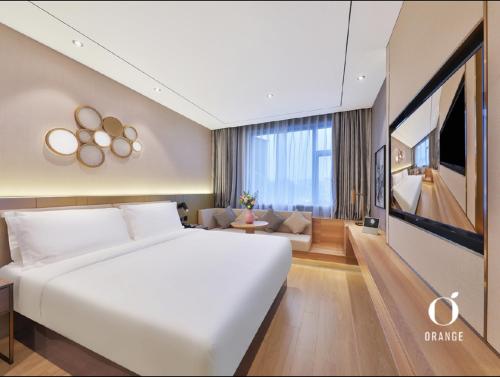 una camera con un grande letto bianco e un soggiorno di Orange Hotel Beijing Yizhuang Rongjing West Street a Pechino
