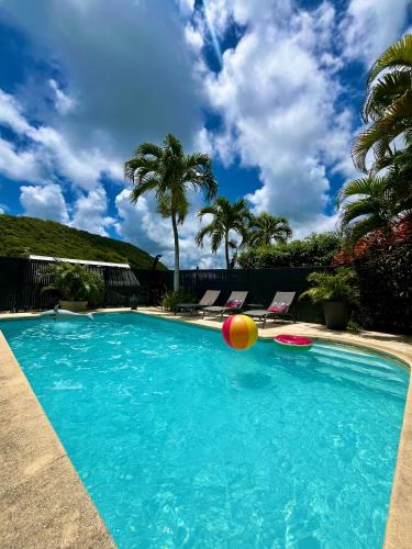 una piscina con una pelota de playa y dos sillas en Villa dO, en Sainte-Anne