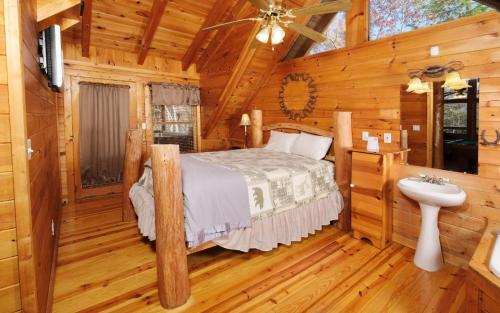 a bedroom in a log cabin with a bed and a sink at Tennessee Treasure in Pigeon Forge
