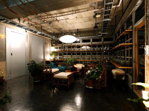 a room with tables and chairs and plants in it at Hotel UNTEN INN in Nago
