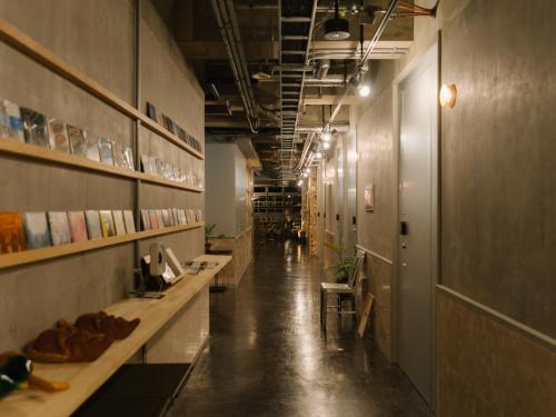 a long hallway with tables and shelves in a building at Hotel UNTEN INN in Nago