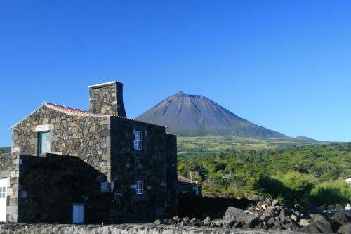 a stone building with a mountain in the background at Yes Pico in Santa Luzia