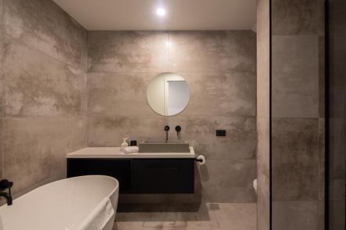 a bathroom with a tub and a sink and a mirror at Sky Villa A in Queenstown