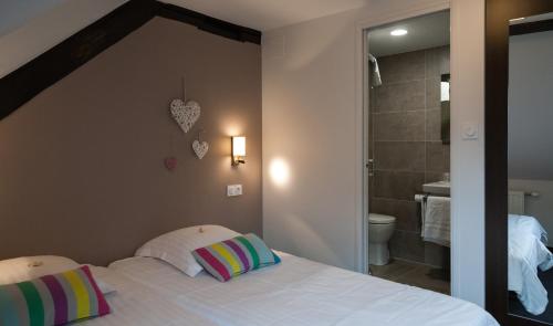 1 Schlafzimmer mit einem weißen Bett und einem Badezimmer in der Unterkunft Hôtel le Saint Nicolas in Riquewihr