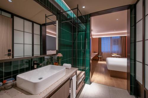a bathroom with a white sink and green tiles at Orange Hotel, Beijing Changping Subway Station, Science and Technology Park in Beijing