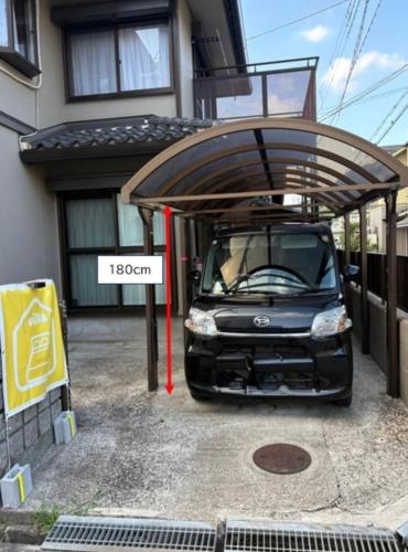 a car parked under a cover in front of a house at HIKONE-Step 彦根ステップ 彦根駅徒歩4分 軽自動車用無料駐車場 彦根城徒歩15分 15名まで 戸建貸切 in Hikone