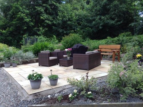a patio with chairs and a bench in a garden at The BurnHowf apartment in Balloch