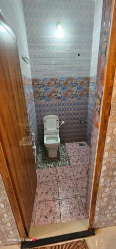 a bathroom with a toilet and a wooden door at ManuDeluxe Stay in Māvalli