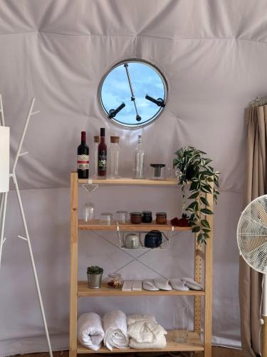 a clock on a wall above a shelf with towels at Batanes Glamping 