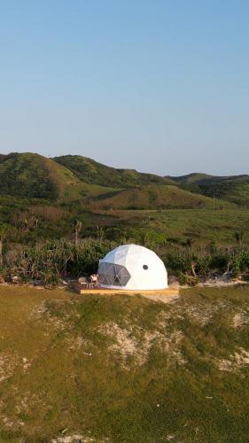 a dome tent on top of a grassy hill at Batanes Glamping 