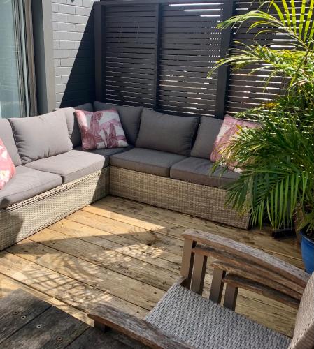 a couch on a patio with two chairs at Allambie Guest House in Frenchs Forest
