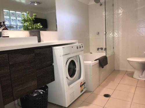 a white bathroom with a washing machine in a bathroom at Allambie Guest House in Frenchs Forest