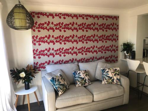 a couch in a living room with a red wall at Allambie Guest House in Frenchs Forest