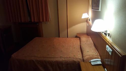 Una cama pequeña en una habitación de hotel con reloj. en Hotel del Sol, en Motilla del Palancar