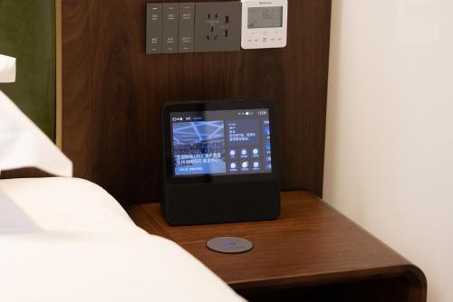 a tablet sitting on a table next to a bed at Nostalgia S Hotel Hangzhou West Lake & Hefang Old Street 时光漫步S酒店杭州西湖湖滨河坊街店 Free fresh ground coffee,Free laundry service in Hangzhou