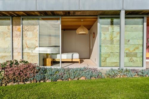 a bedroom in a house with large glass windows at Waiheke Island Coastal Retreat in Waiheke Island