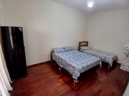 two beds in a room with wooden floors at Casa de serenidade e paz in Alfenas