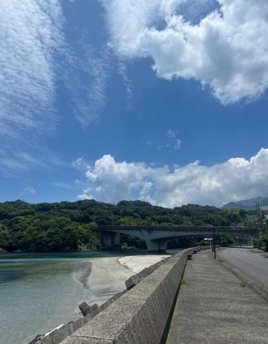 屋久島にあるAnbo-ingの青い空と雲が見える川にかかる橋