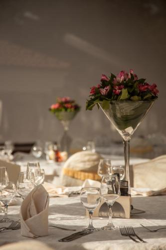 a table with glasses and a vase with flowers in it at Hotel Bellevue in Skopje