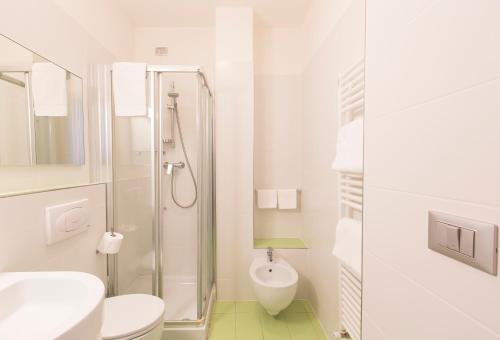 a white bathroom with a toilet and a sink at Hotel Trieste Mare in Lignano Sabbiadoro