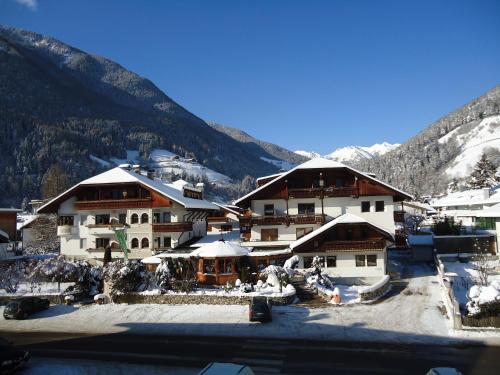 a large building with snow covered mountains in the background at Alphotel Stocker Alpine Wellnesshotel in Campo Tures