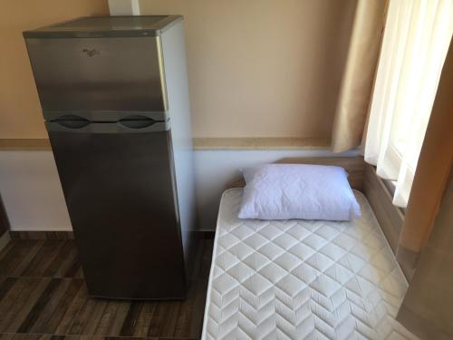 a small room with a refrigerator and a bed at Family Hotel Malibu in Chernomorets