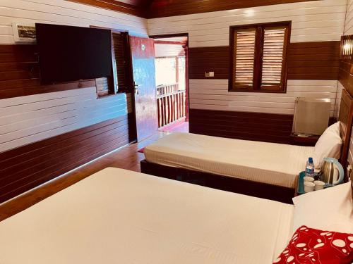 a room with two beds and a flat screen tv at Anandas Beach Resort in Trincomalee