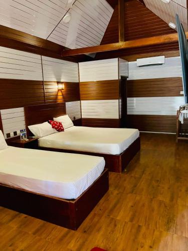 two beds in a room with wooden walls and wood floors at Anandas Beach Resort in Trincomalee