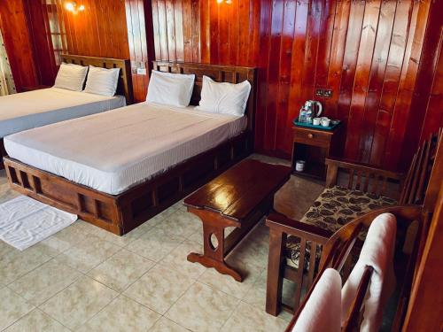 two beds in a room with wood paneled walls at Anandas Beach Resort in Trincomalee