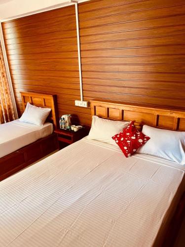 two beds in a room with wooden walls at Anandas Beach Resort in Trincomalee