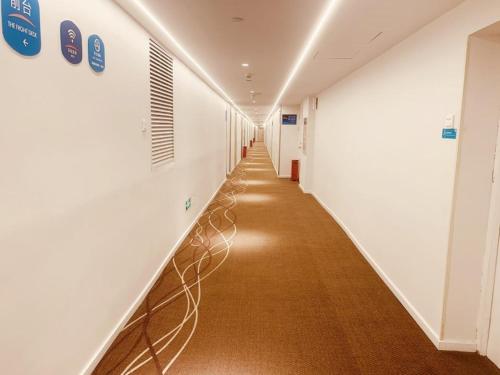 a long hallway with white walls and a long hallway at Hanting Hotel Beijing Century Jinyuan Changchun Bridge Subway Station in Beijing