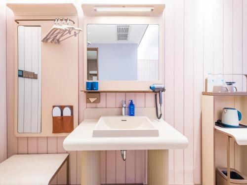 une salle de bain avec un lavabo blanc et un miroir dans l'établissement Hanting Hotel Beijing Yizhuang Creative Life Plaza Cultural Park, à Pékin