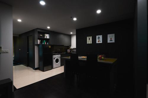 a kitchen with black walls and a table with a washing machine at 42Grand Residence in Bangkok