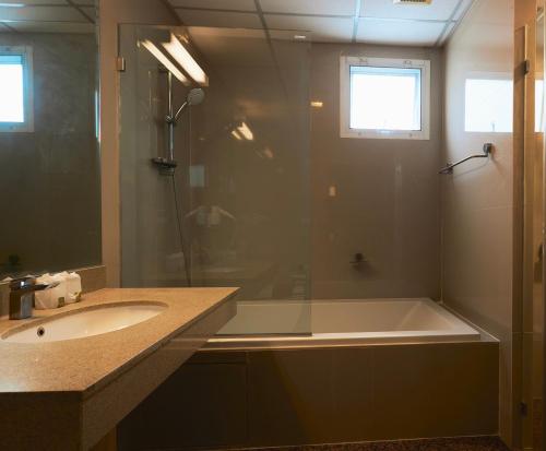 a bathroom with a shower and a tub and a sink at 42Grand Residence in Bangkok