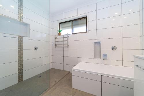a white bathroom with a sink and a window at 4BR Coastal Retreat With Pool in Pialba