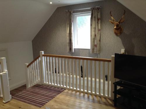 a room with a white crib and a window at The BurnHowf apartment in Balloch