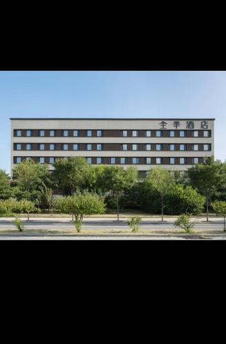 un edificio alto con árboles frente a una calle en JI Hotel Beijing Fangshan Changyang Aerospace City Electronics Technology Park, en Beijing