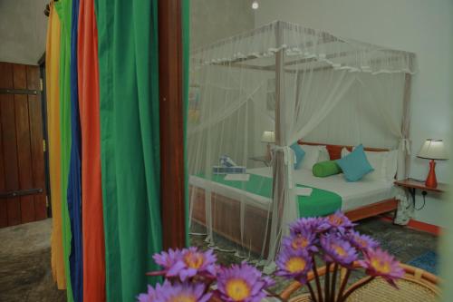 a bedroom with a bed with a canopy and flowers at Villa Gaetano Unawatuna in Unawatuna
