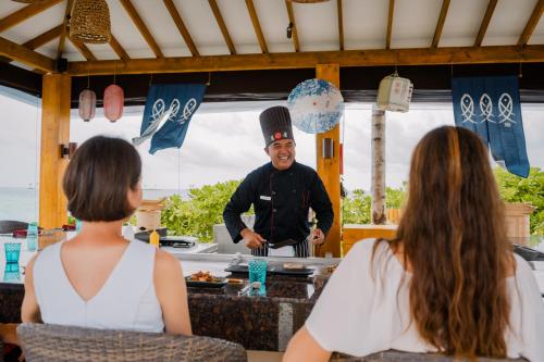 a man in a top hat standing in a kitchen with two women at Joy Island Maldives All Inclusive Resort in Male City